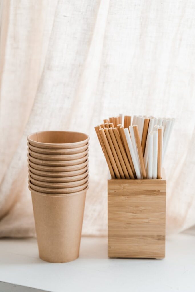 Stack of Brown Paper Cups near the Wooden Box of Drinking Straws